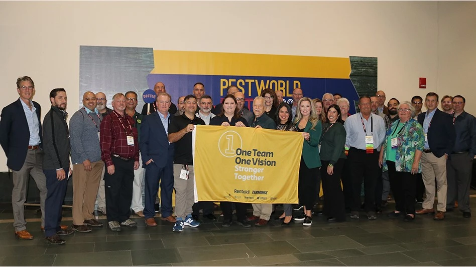 Members of Rentokil and Terminix who are attending NPMA PestWorld gathered for a picture in front a sign reading "One Team One Vision Stronger Together."